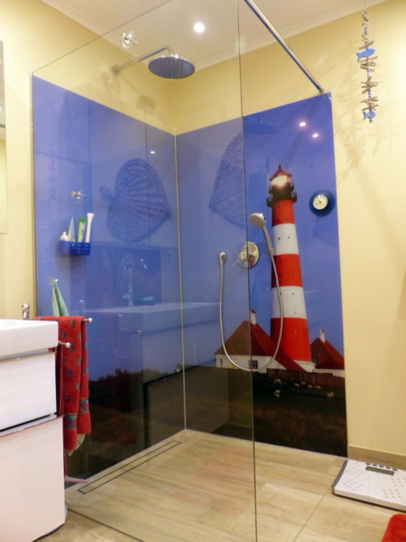 Walk-in-Dusche mit blauem Leuchtturm-Motivdruck auf der Glasrückwand