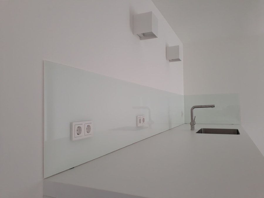 Weiße Glas-Küchenrückwand mit integrierten Steckdosen