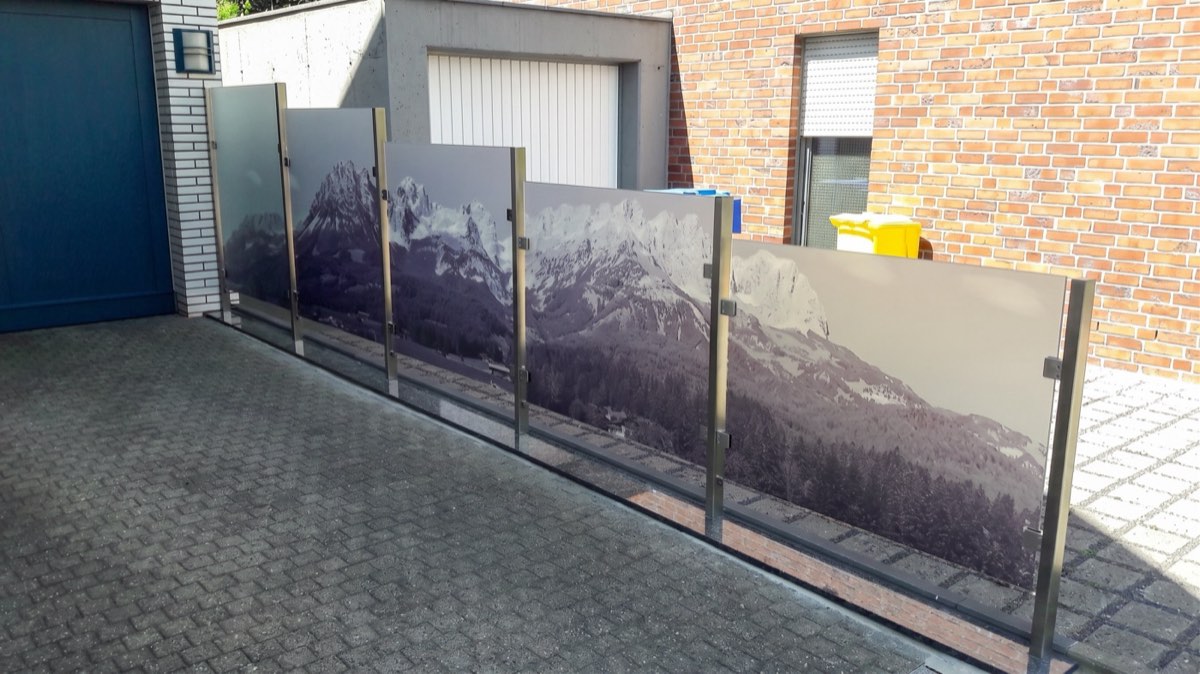 Glas-Windschutz mit Motivdruck vor einem Wohnhaus